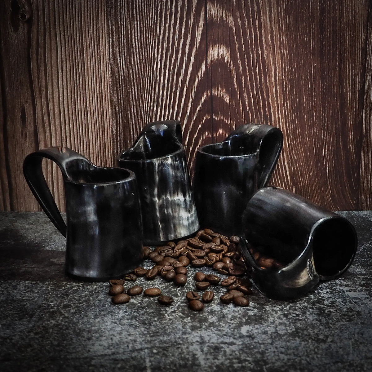 Sett med fire espressokopper – alle fire koppene med kaffebønner, mot trevegg