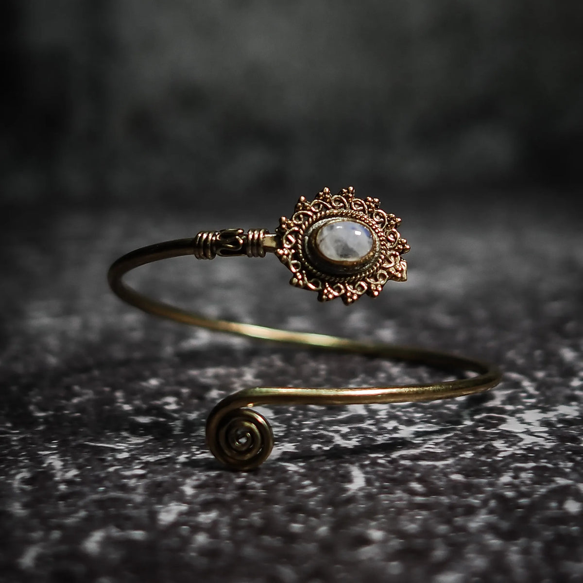 Vikingarmband i vit/grå halvädelsten med ornamenterad filigre och spiralformad terminal på texterad bakgrund