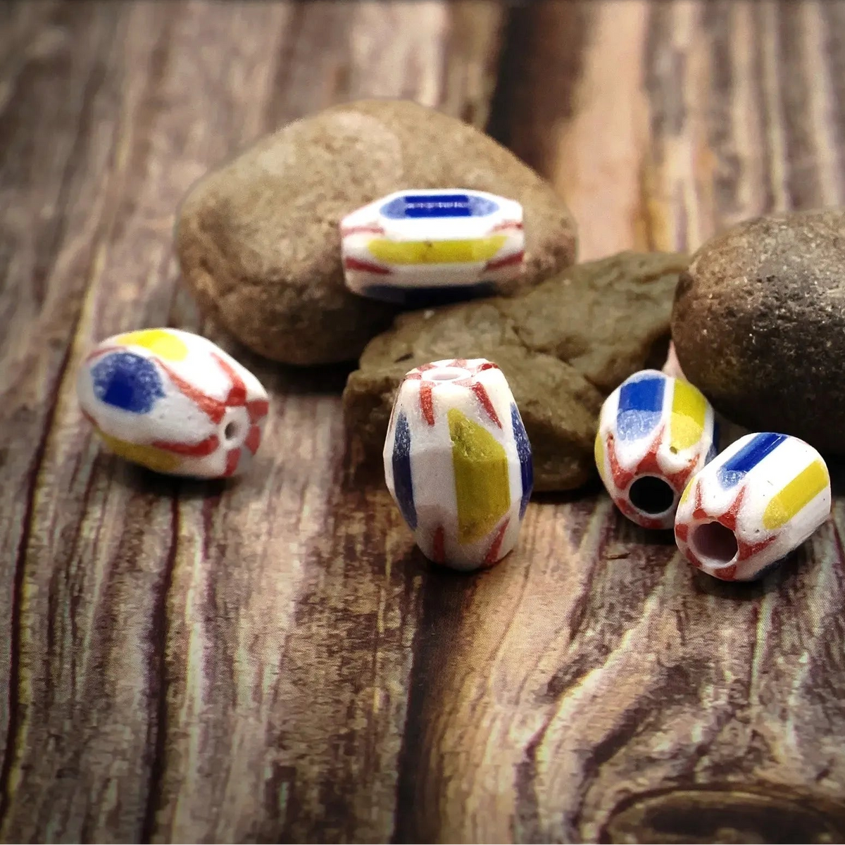Oval multicolored glass bead – blue, yellow and red pattern on white base