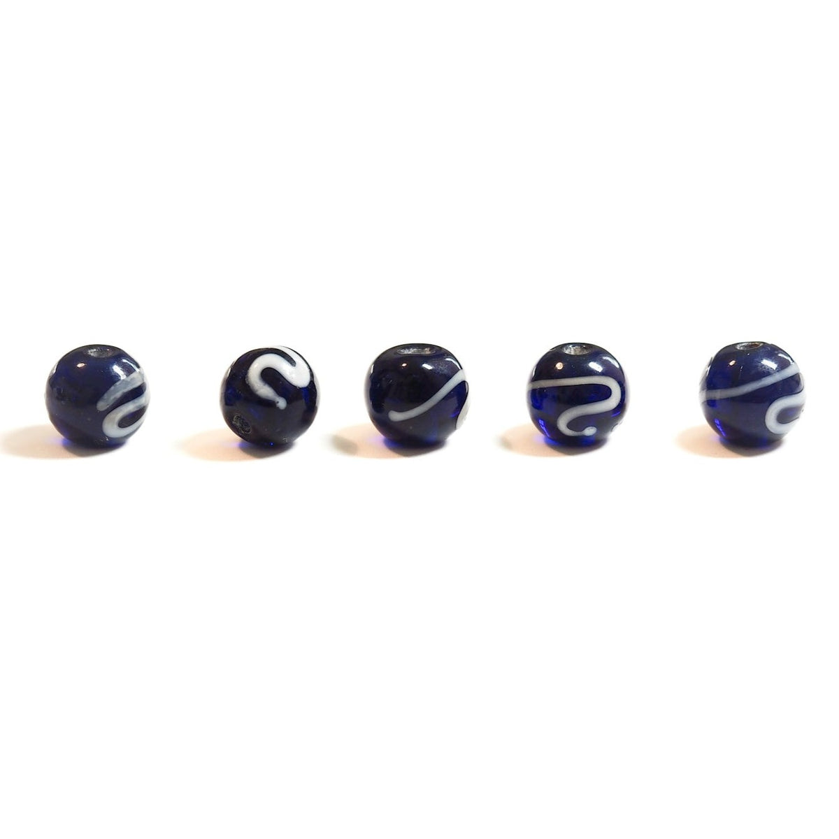 Five blue glass beads with white spiral patterns, photographed on neutral background