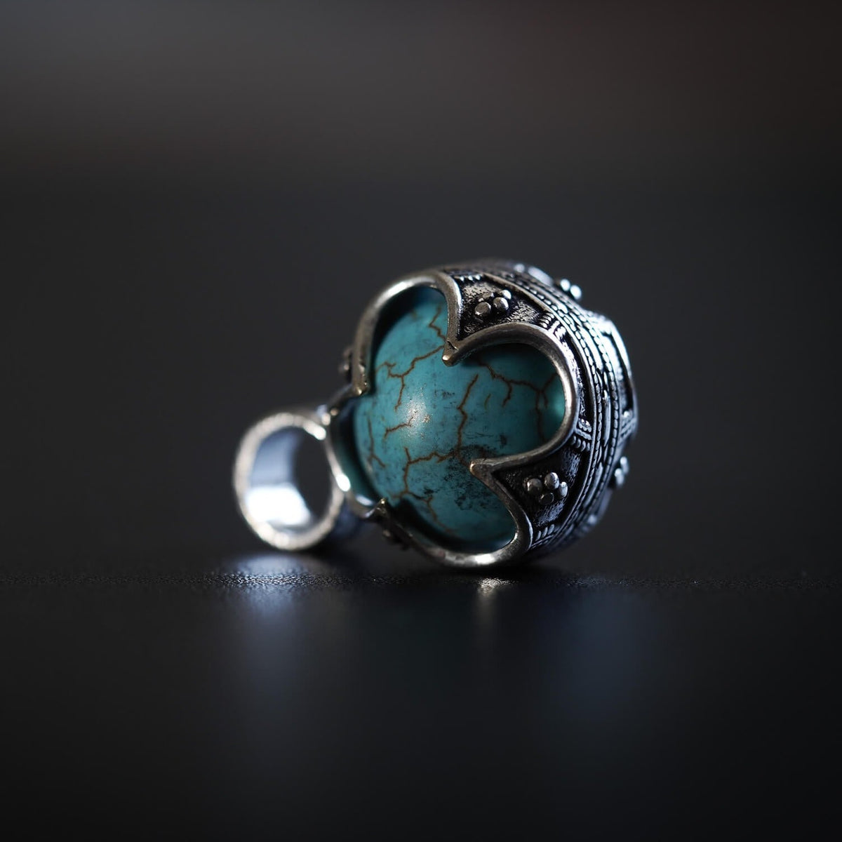 Gotländsk mässinghänge med turkos-sten, visar ornamental silverglansigt metallarbete och stenens naturliga veningar