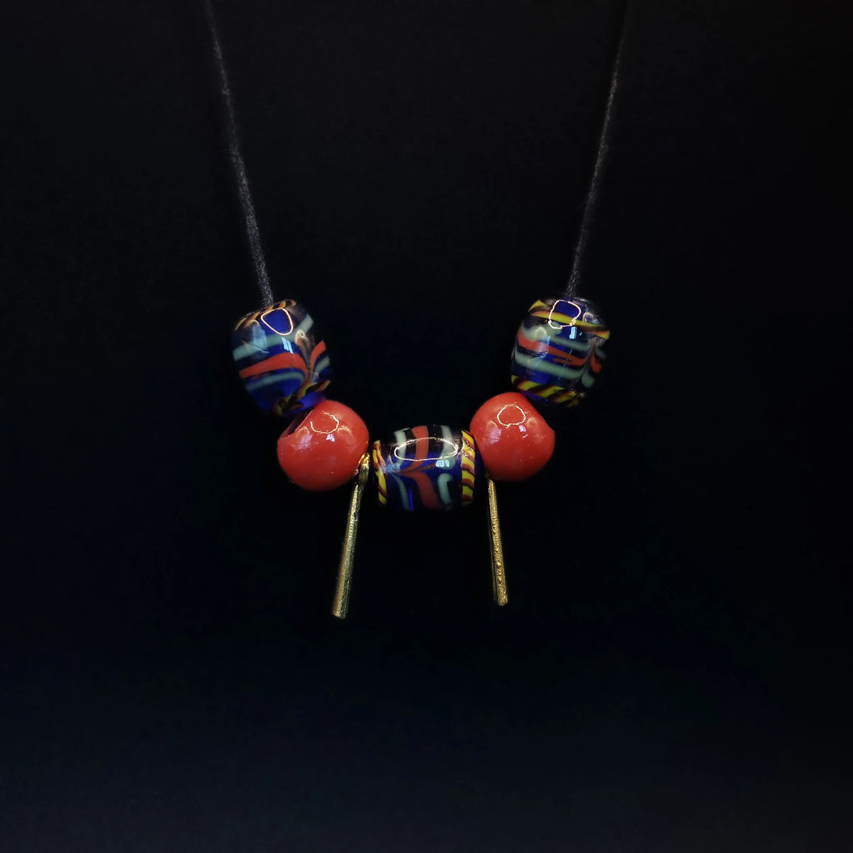 Två identiska stavpärlor av mässing på vit bakgrund. Cylindriska pärlor med guldmetallic färg, hammrad yta och patina. Ögonkrokar för trådning. Smycke-komponenter.