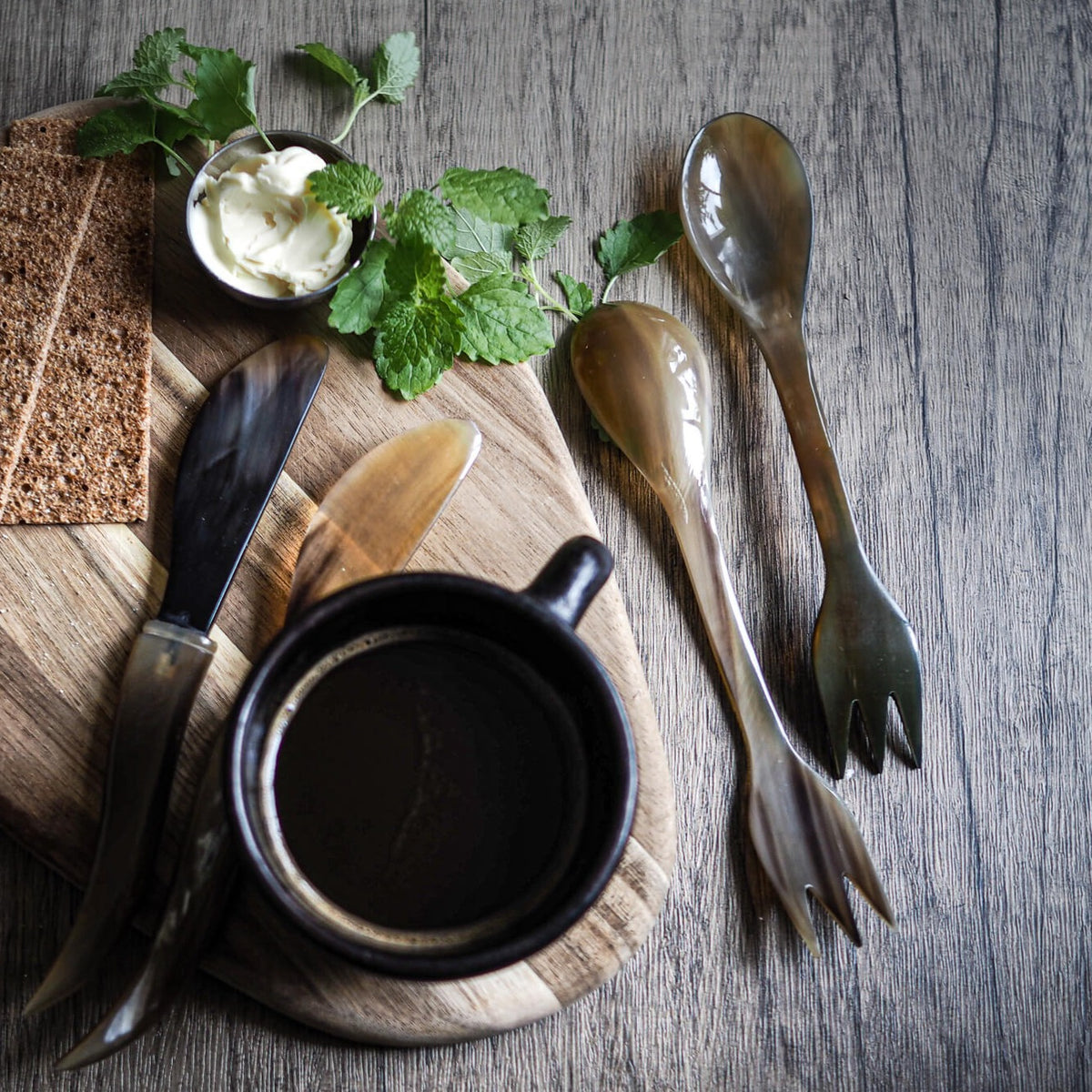 Två ljusa oxhorn-sporks presenterade vertikalt sida vid sida. Båda visar gaffol och skalkis-ändamål. Naturligt horn med kornmönster. Rent, katalog-lämpat produktfoto.