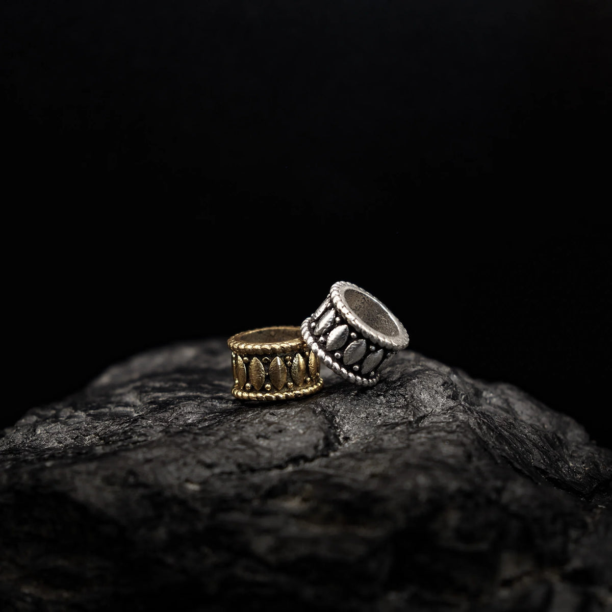 Skäggpärla-Nana, mässing, med stenar, på mörk sten.