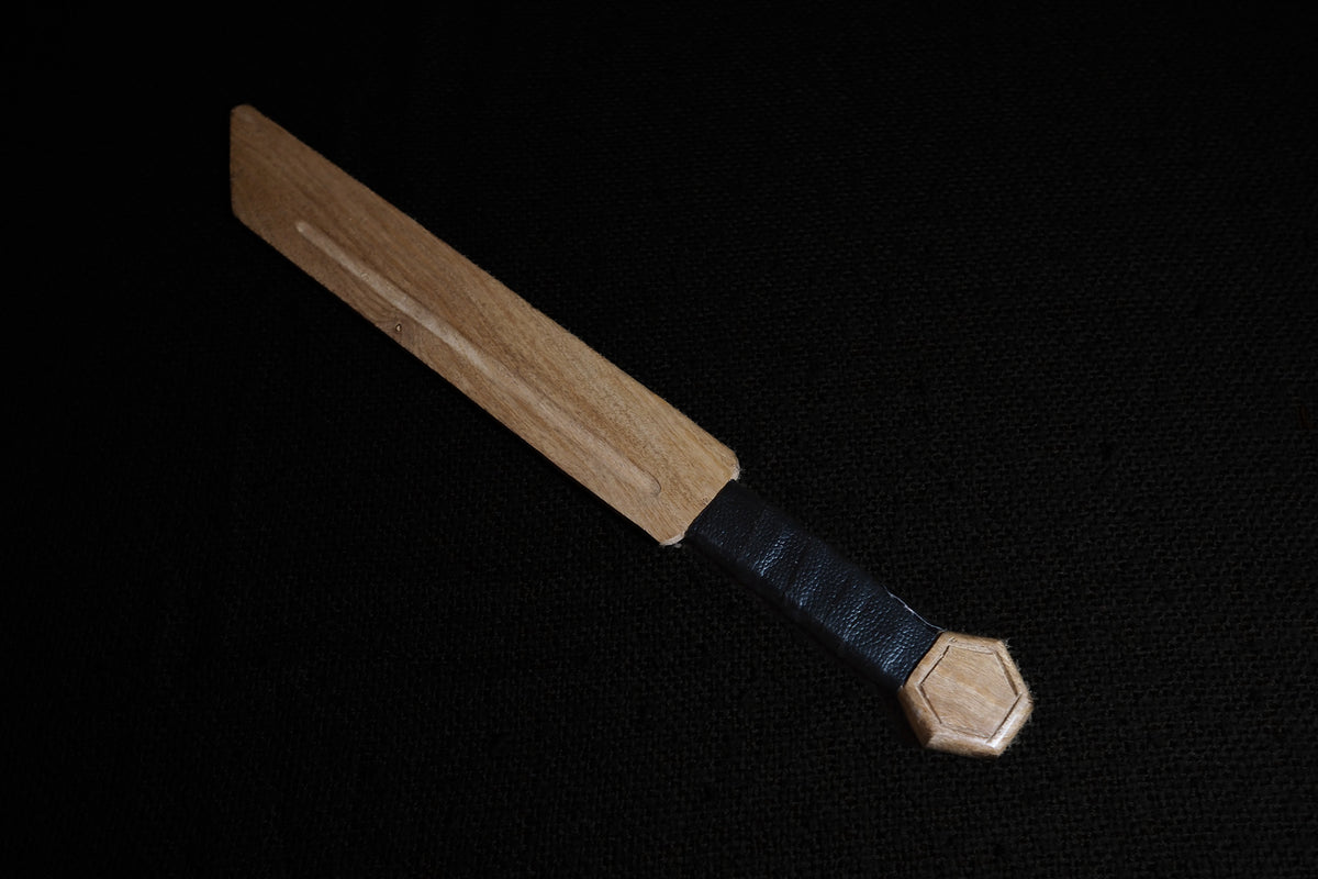 Wooden seax sword, leather, on wood.