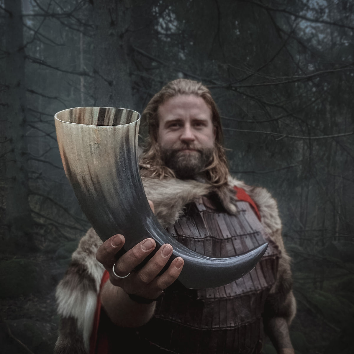 Stort drikkehorn på ca 800ml, holdt av en vikingkledd mann i skogsmiljø, viser autentisk bruk av hornbegeret