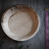 Stor engångstallrik i palmblad på grå trä, fotograferad från ovan med måttlinjal för storleksreferens.