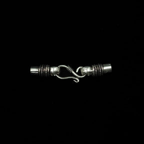 Halsbandslås i silver med S-krok och ornerade ändhylsor mot svart bakgrund