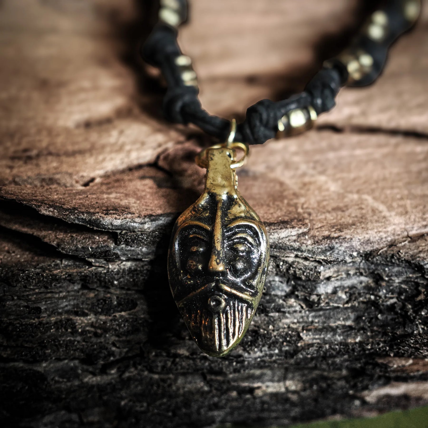 Odin necklace – the god mask in close-up against a tree trunk