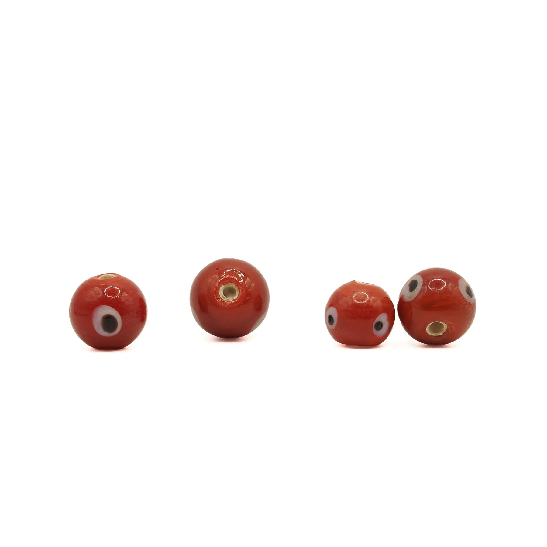 Red glass bead Birka – four beads in a row, eyes with black pupils and the hole facing the camera