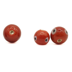 Red glass bead Birka – three beads, one with the hole facing the camera and two with eyes on the side