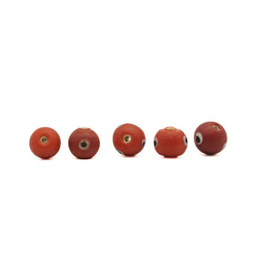 Red glass bead with eye – five beads in a row, seen from the side and through the hole