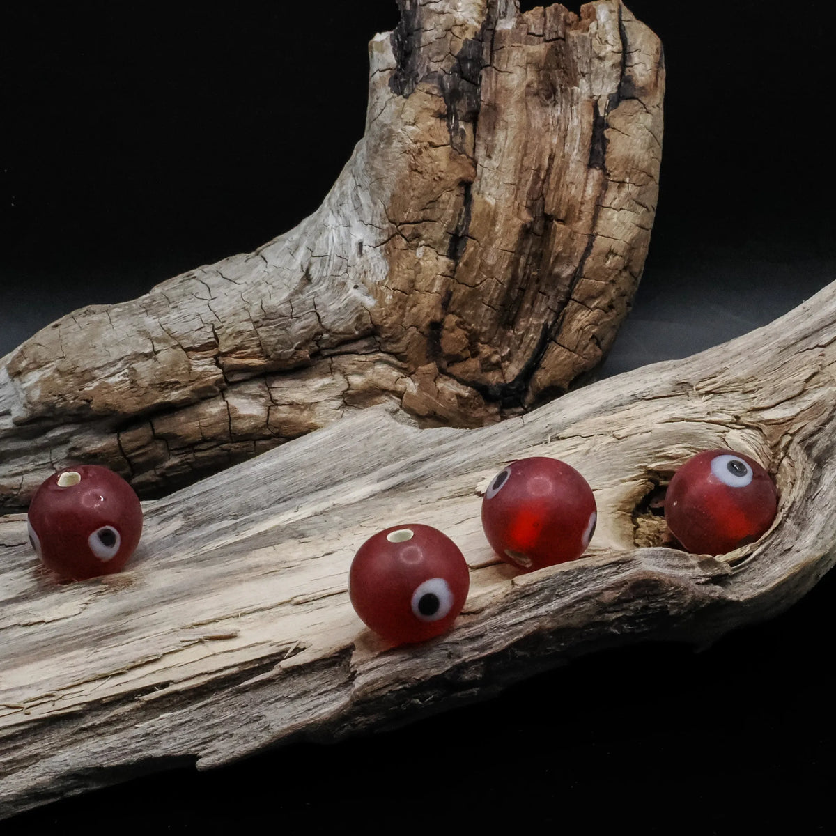 Red glass bead with eye – four beads with white eyes and visible holes, seen from different angles