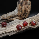 Red glass bead with eye – four beads with white eyes and visible holes, seen from different angles
