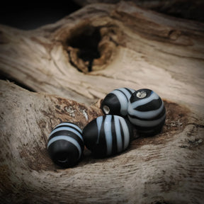 Black glass bead with white decoration – four beads together, white stripes and holes visible