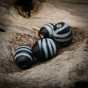 Black glass bead Gotland – four beads with white stripes, two with visible hole at the end
