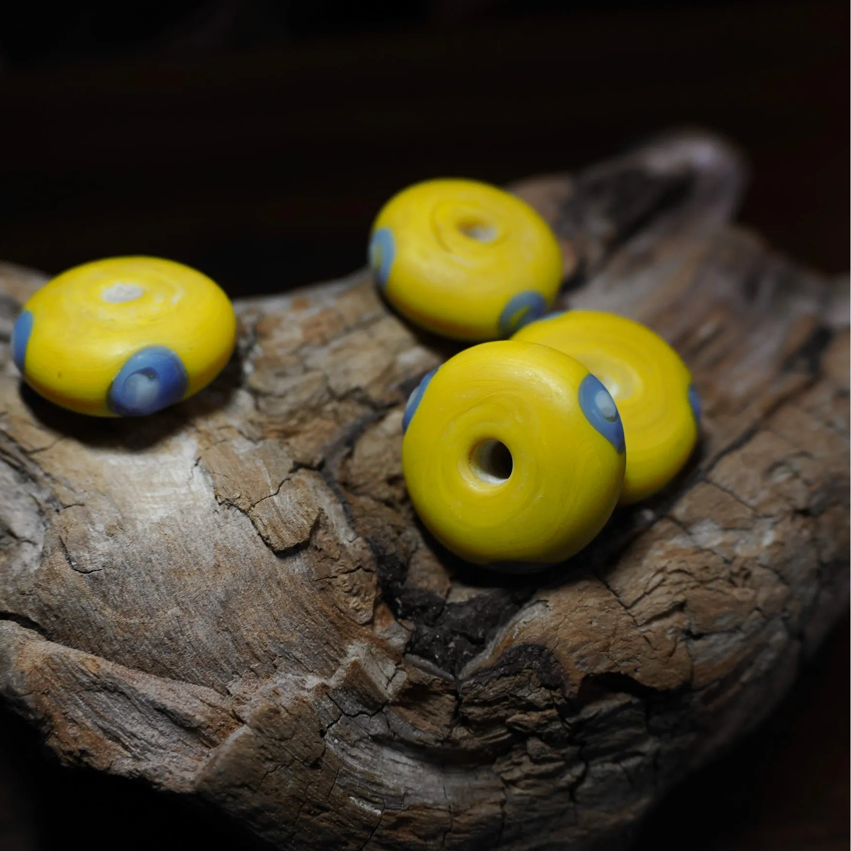 Yellow glass bead Ribe – four beads with blue eyes, hole and sides visible