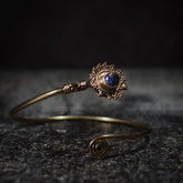 Vikingarmband i mörkblå halvädelsten med dekorativ mässingfiligre och spiralformad terminal på mörk bakgrund