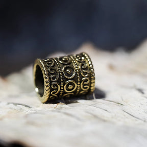Golden polished brass beard bead displaying scrollwork and circular embossed ornament detail