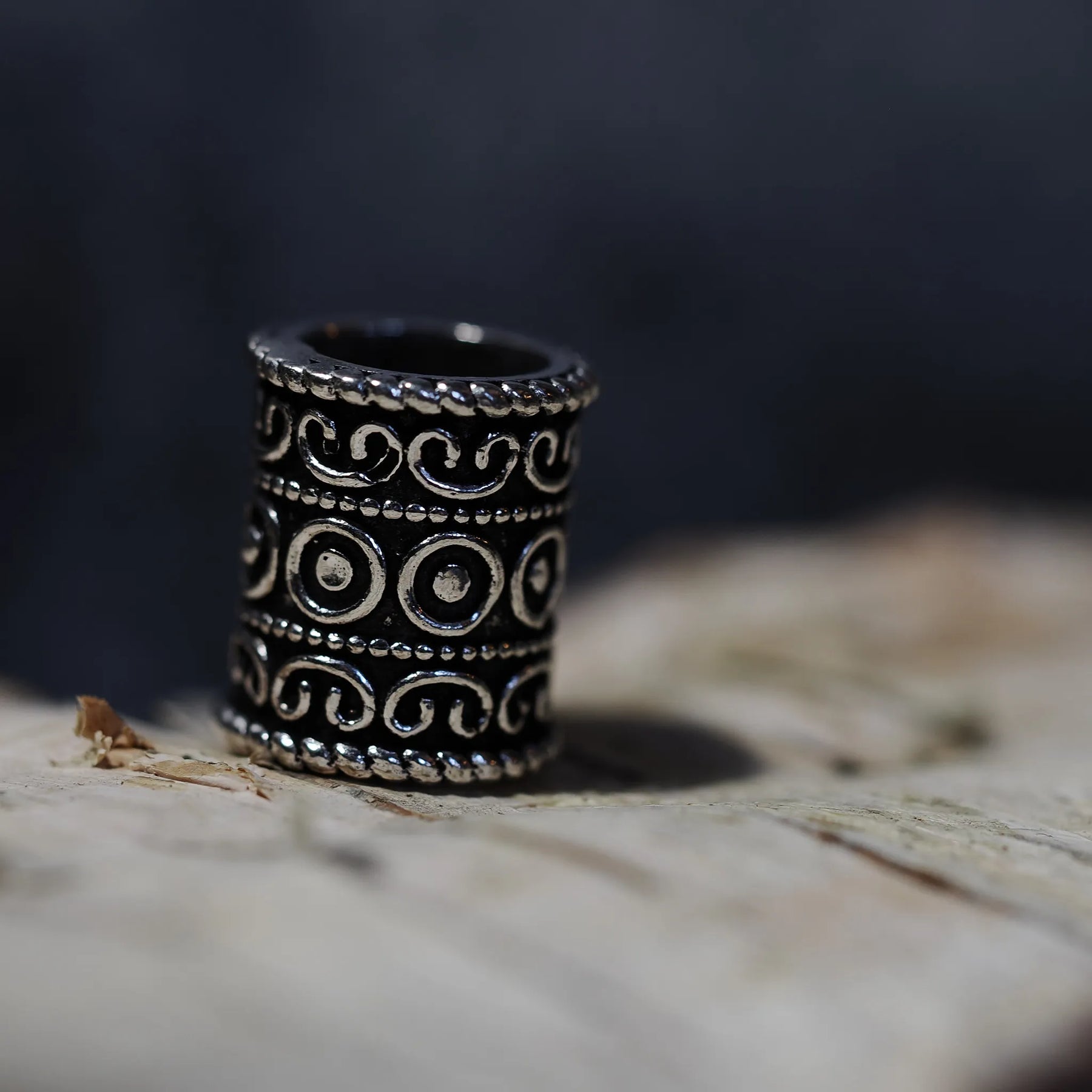 Upright brass beard bead with three-dimensional scrollwork and circular relief detail