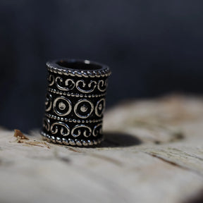 Upright brass beard bead with three-dimensional scrollwork and circular relief detail