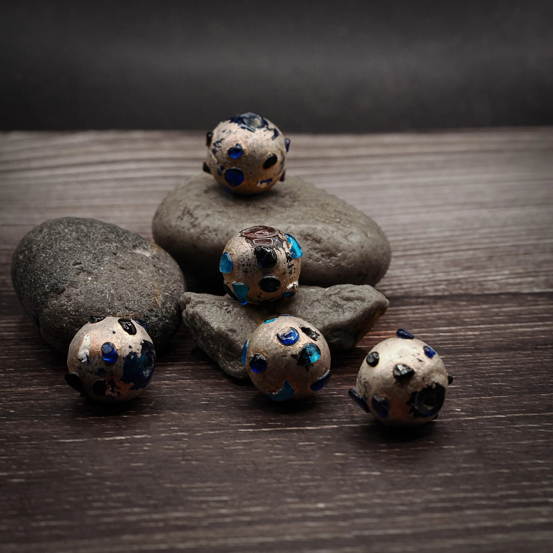 Metallisk glaspärla med turkosa prickar, 12mm diameter, på naturlig stenbakgrund för produktvisning