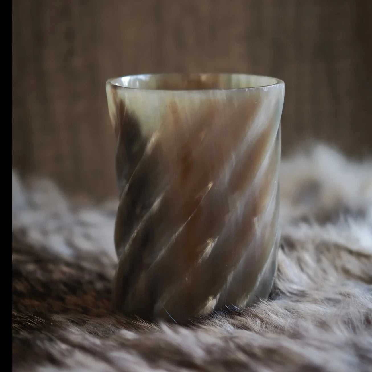 Hornglasögon med handsnidad spiraldesign, visar elegant vriden form och organiska randiga mönster mot neutral bakgrund.