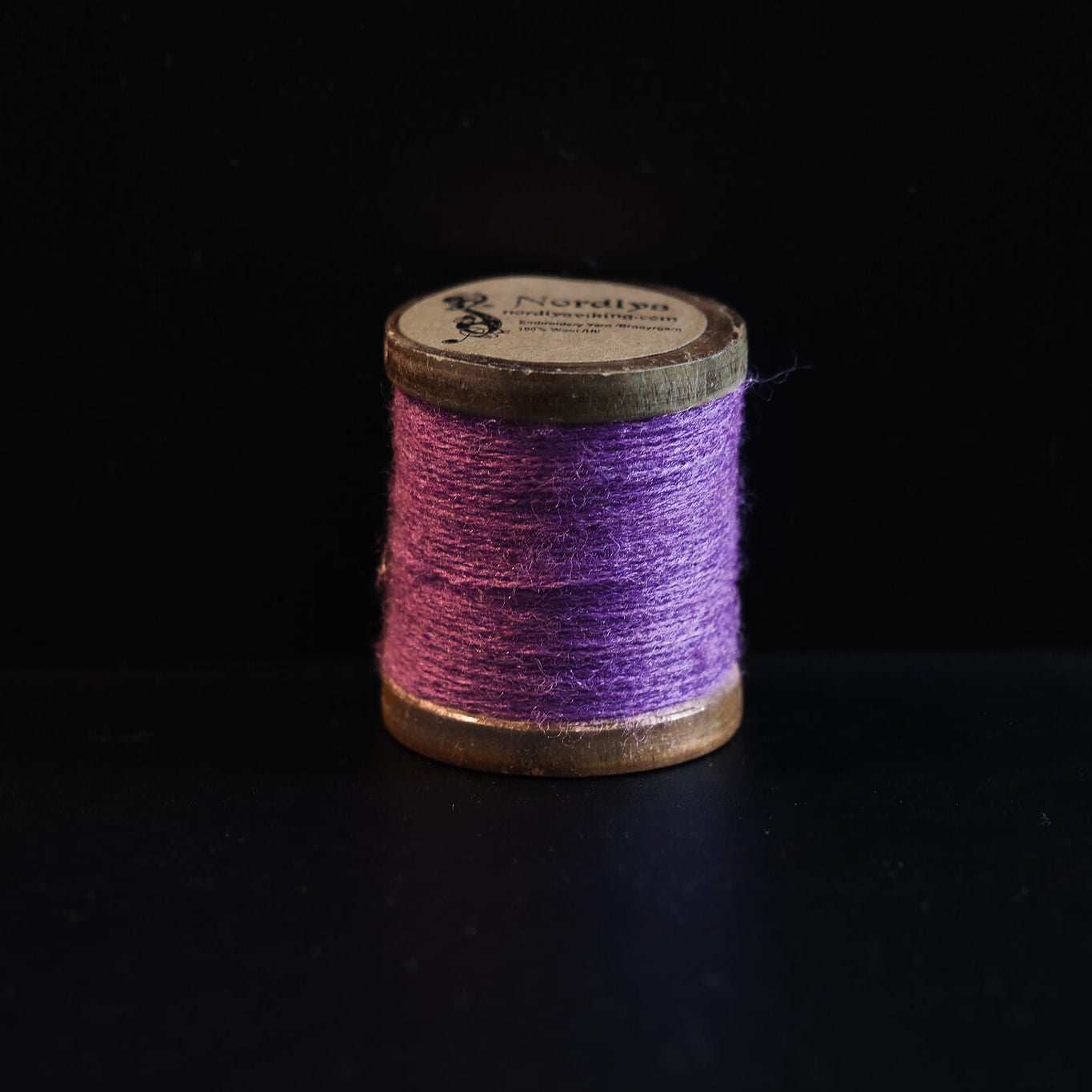 Rosa-lila brodertråd på trätrumlor med Nordlys-märkning. Mjuk färgton lämplig för detaljerad Viking-inspirerad broderi och traditionellt hantverk.