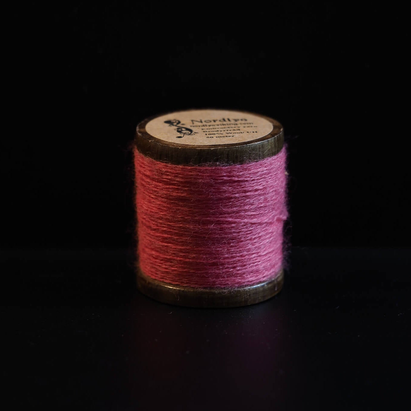 Röd brodertråd på traditionella trätrumlor med Nordlys-märkning. Djup röd färg inspirerad av Viking-dräkter och traditionell Skandinavisk broderi.