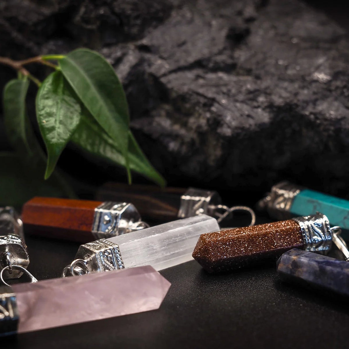 Stone pendant, Selenite – among several stone pendants in different colors, group shot with a green leaf
