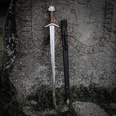 Vikingsverd Kungarnas Dal – dratt sverd og slire lent mot runestein utendørs