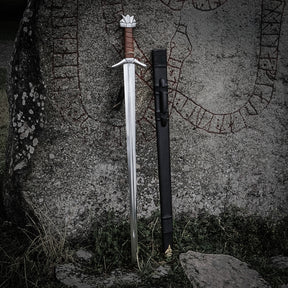 Vikingsverd Kungarnas Dal – dratt sverd og slire lent mot runestein utendørs