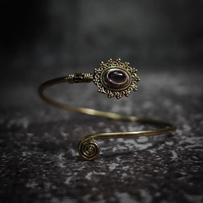 Vikingarmband i lila ametist med dekorativ mässingfiligre och spiralformad terminal på mörk sten