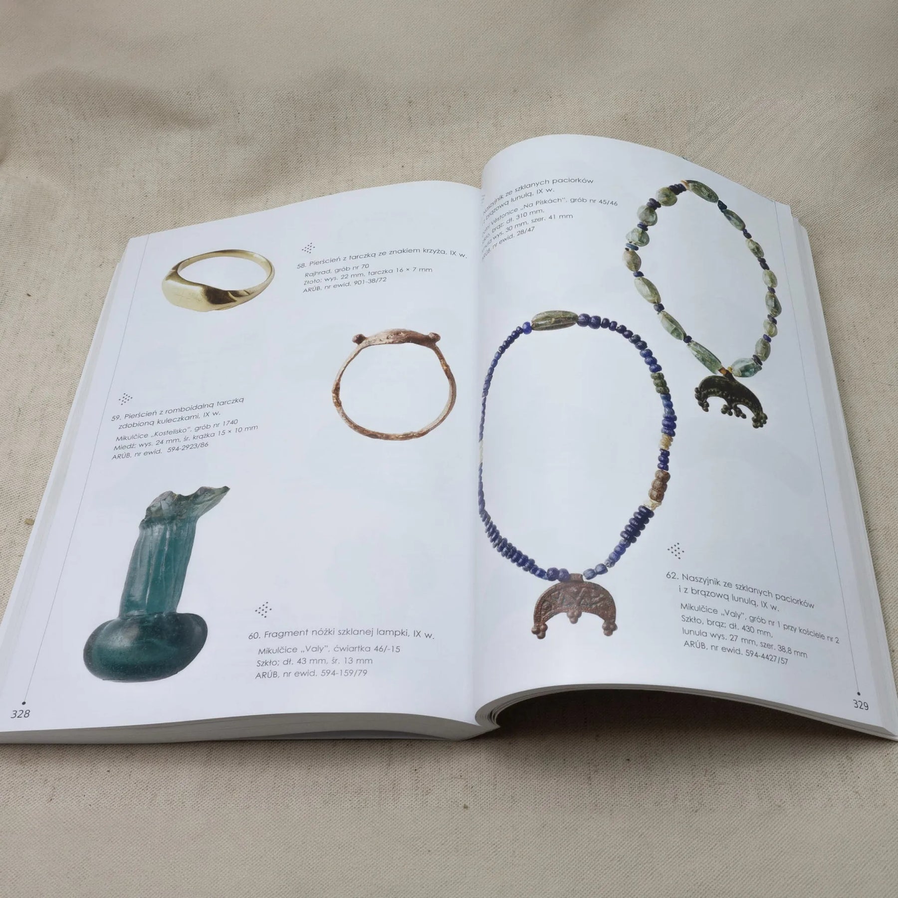 Boken Great Moravia – oppslått ved side med ringer, perlehalskjeder og glassfunn