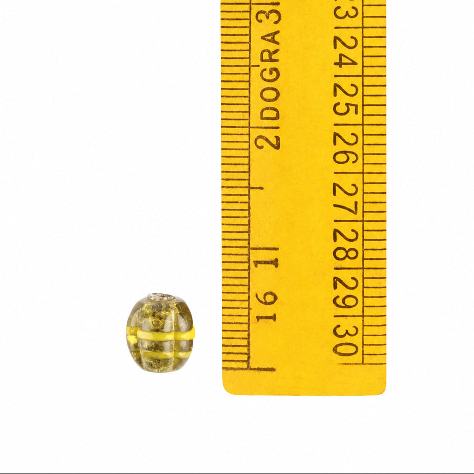 Green melon bead with decoration – a bead next to a yellow folding ruler, the upper part of the scale visible