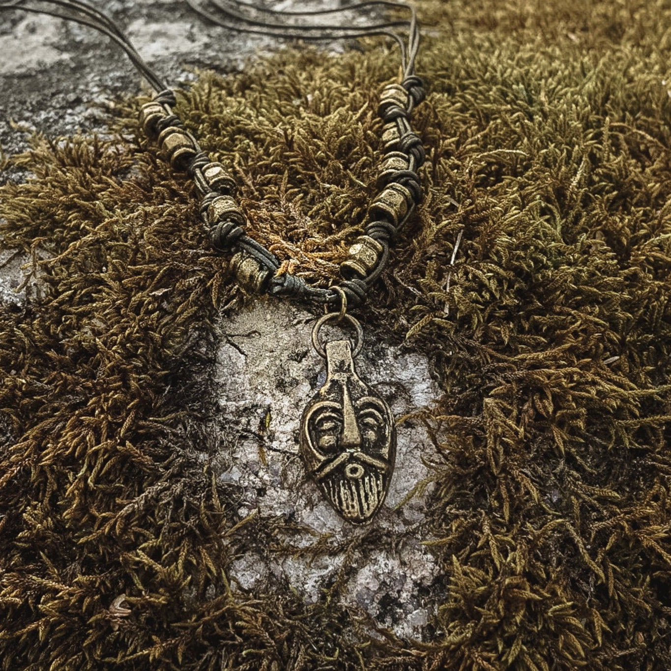 Odin halsband i brons på mossa och sten, visat från ovansidan med naturlig patina synlig